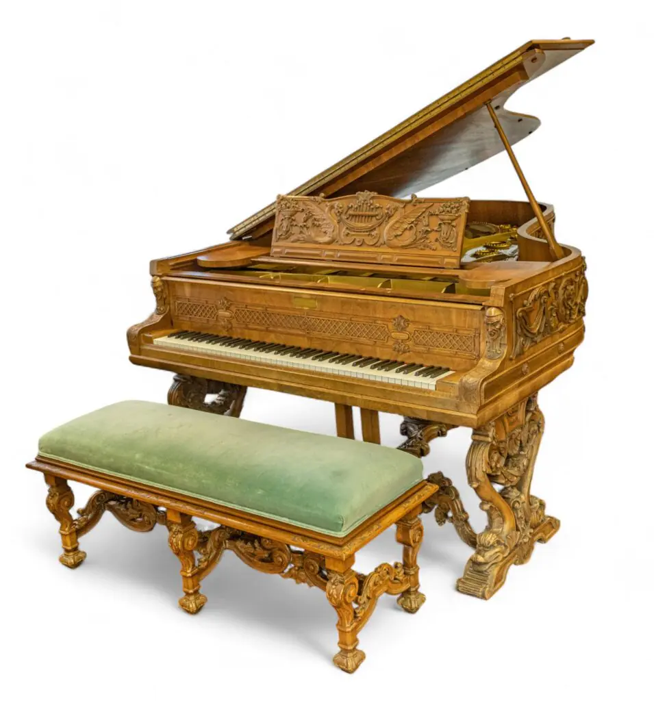 Ornate carved wooden piano with a matching green upholstered bench against a white background.
